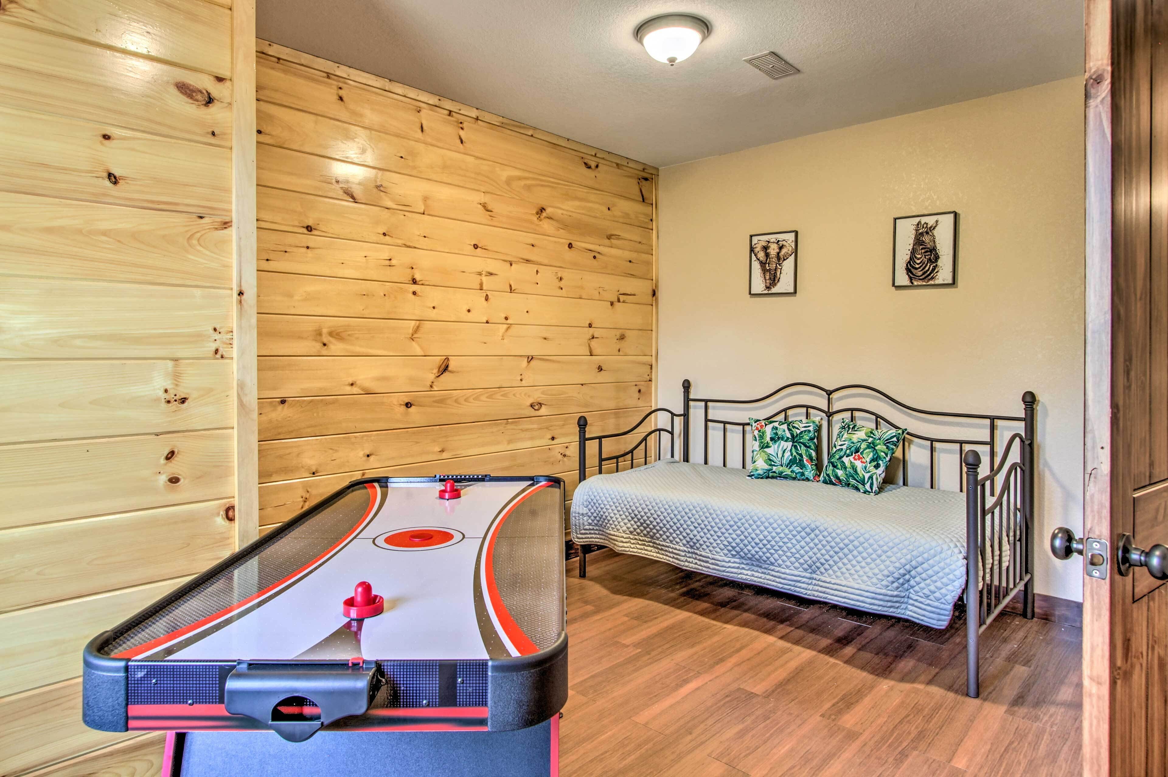 A room with a wooden wall, a bed with a blue quilt, and a foosball table.