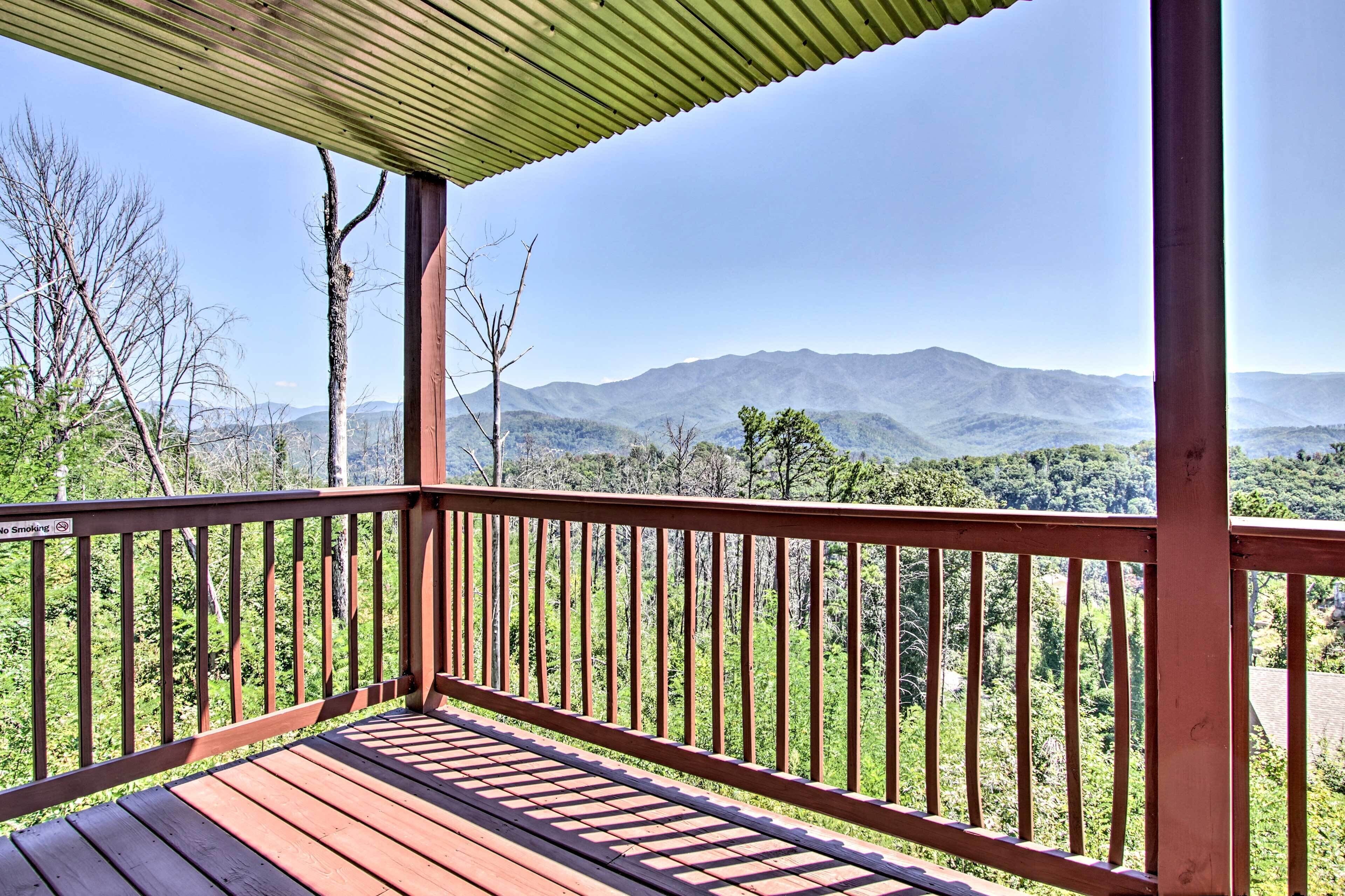 Una terraza de madera con vistas a montañas y bosque.