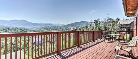 A wooden deck with a view of mountains and a lake.