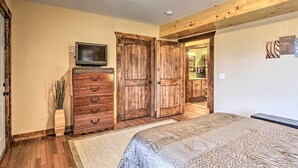 A bedroom with a bed, wooden wardrobe, a television, and a small table with decorative items.