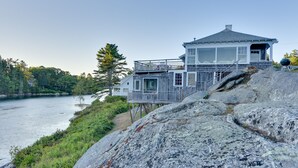 Ein Haus am Wasser mit einer Holzterrasse und Blick auf das Wasser.