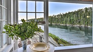 Ein Zimmer mit großem Fenster, Blick auf Fluss und Wald.