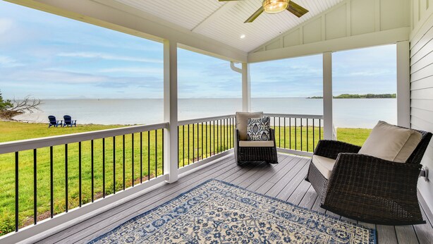 A covered porch with a view of the water, wicker chairs, and a blue patterned rug. - Waterfront Maryland Vacation Home: Private Beach! (Ridge)