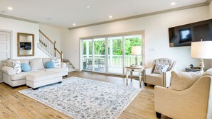 A spacious living room with a large window, a sofa, a chair, and a television. - Waterfront Maryland Vacation Home: Private Beach! (Ridge)