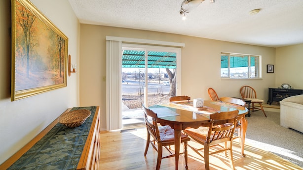 A dining area with a wooden table and chairs, a painting on the wall, and a view through a sliding glass door. - 'cedar House' - Family-friendly Cortez w/ Yard! (Cortez)