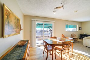 A dining area with a wooden table and chairs, a painting on the wall, and a view through a sliding glass door. - 'cedar House' - Family-friendly Cortez w/ Yard! (Cortez)
