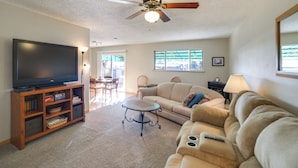 A living room with a flat-screen TV, a ceiling fan, a sofa, a coffee table, and a bookshelf. - 'cedar House' - Family-friendly Cortez w/ Yard! (Cortez)