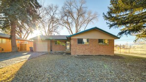 A single-story house with a brick exterior, a front garage, and a small front yard with gravel. - 'cedar House' - Family-friendly Cortez w/ Yard! (Cortez)