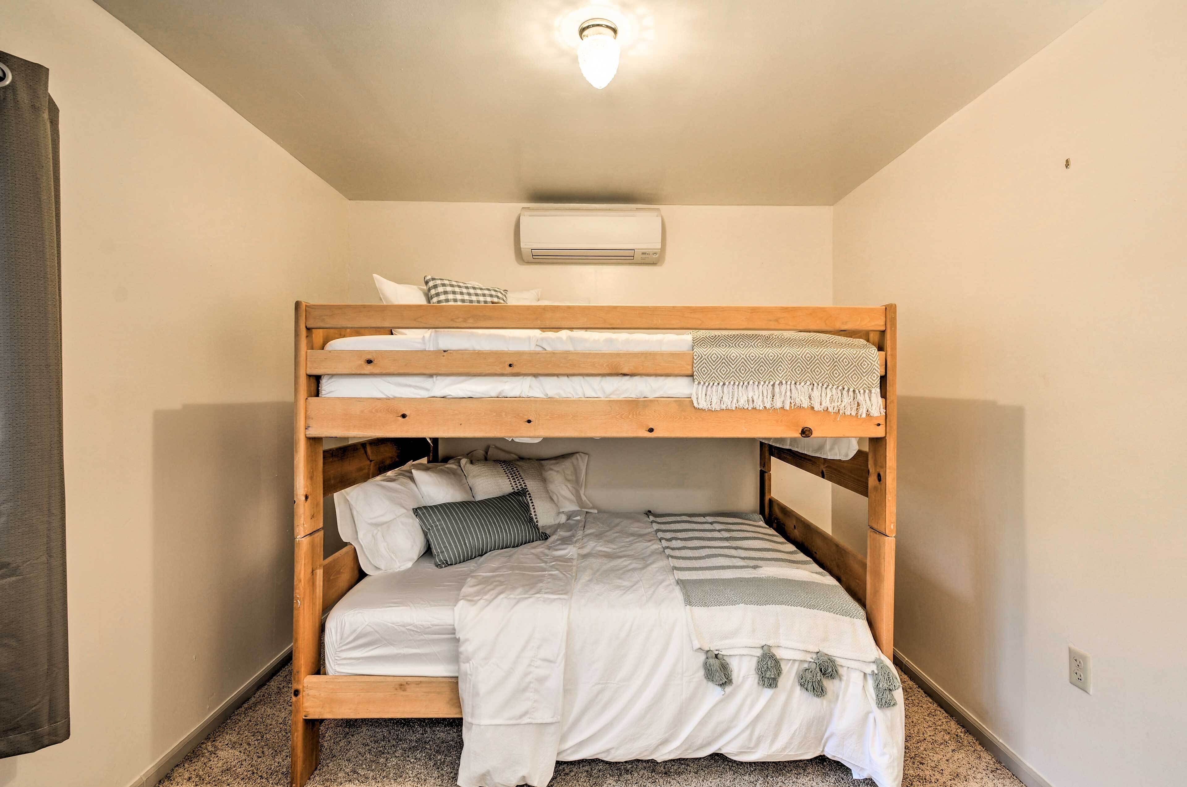 A bunk bed room with a ceiling light, an air conditioner, and a carpeted floor.