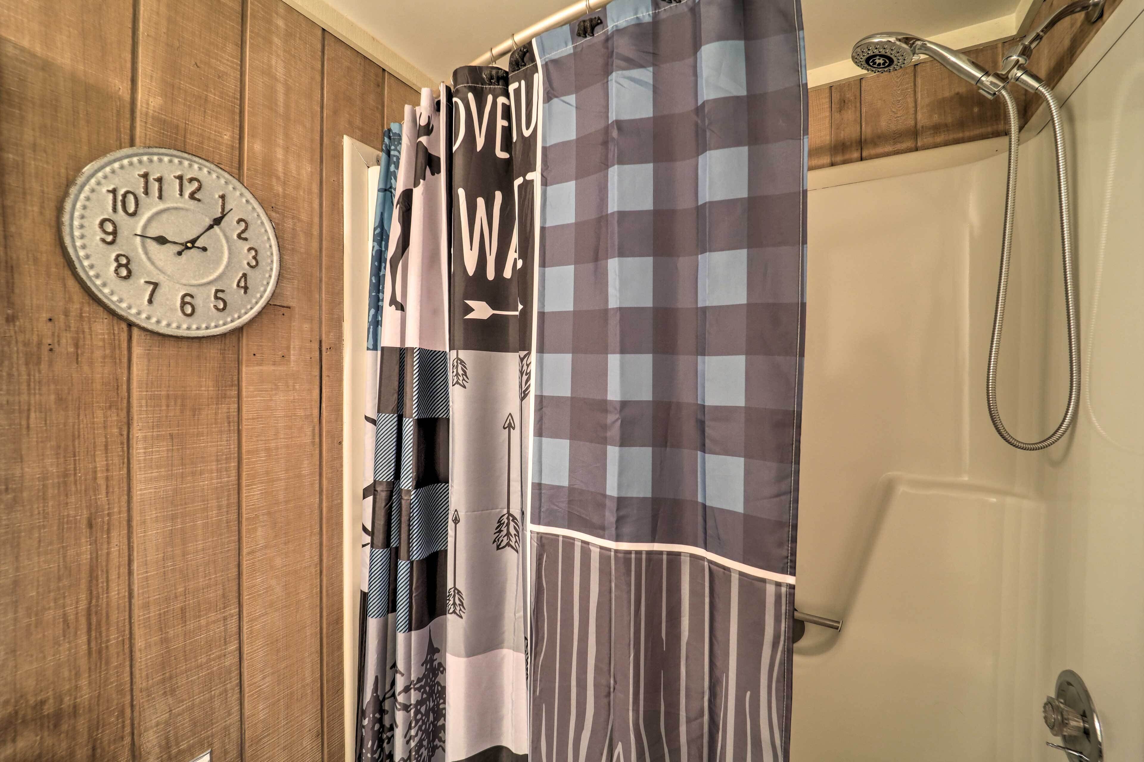 Ein Badezimmer mit Holzwand, einer Uhr, einer Dusche und einem karierten Duschvorhang.