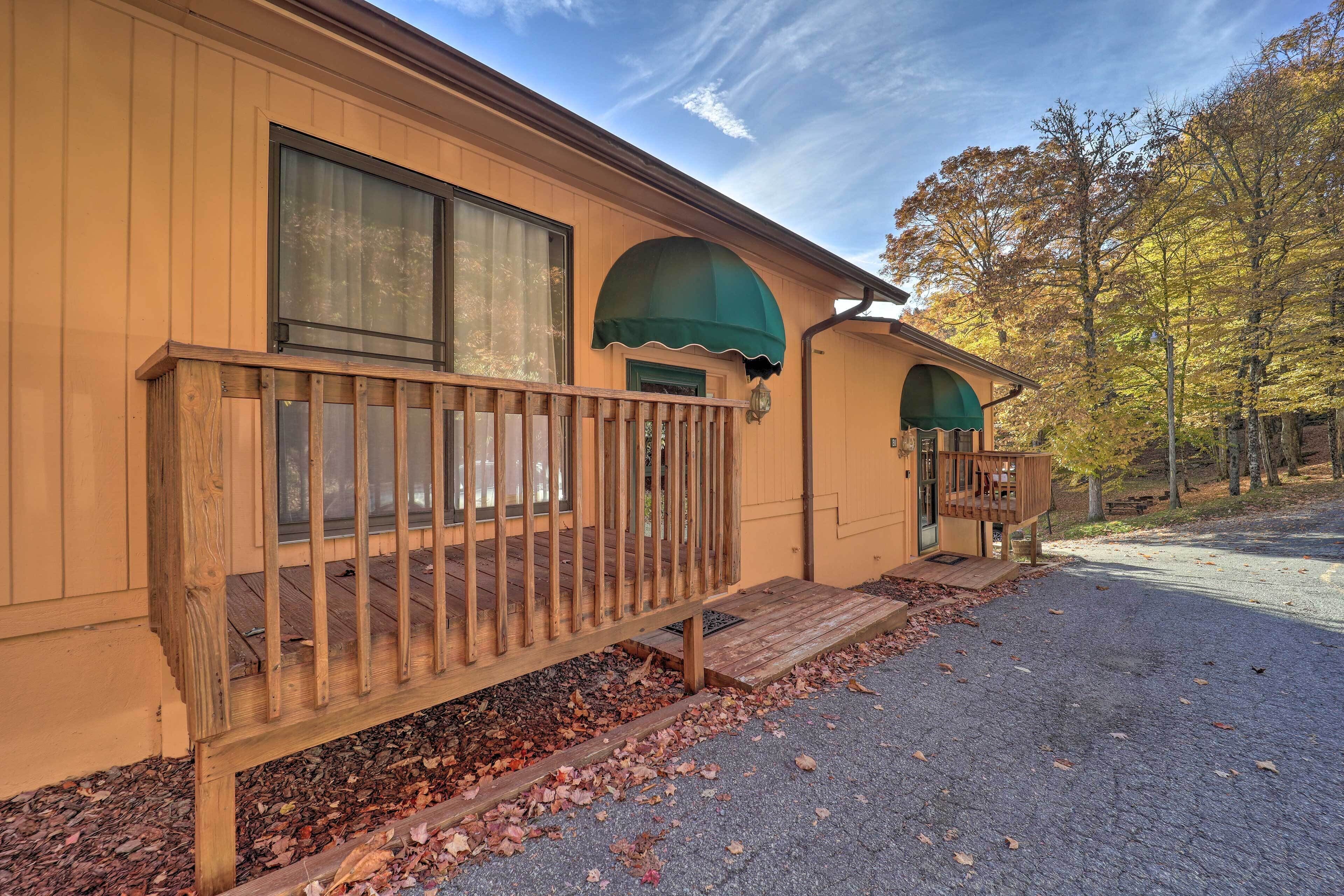 A wooden cabin with a porch, a covered entryway, and a driveway.