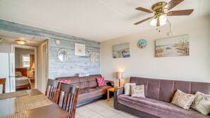 Ein Wohnzimmer mit einem Holzespeisetisch, zwei Sofas, einem Deckenventilator und Kunstwerken an den Wänden.