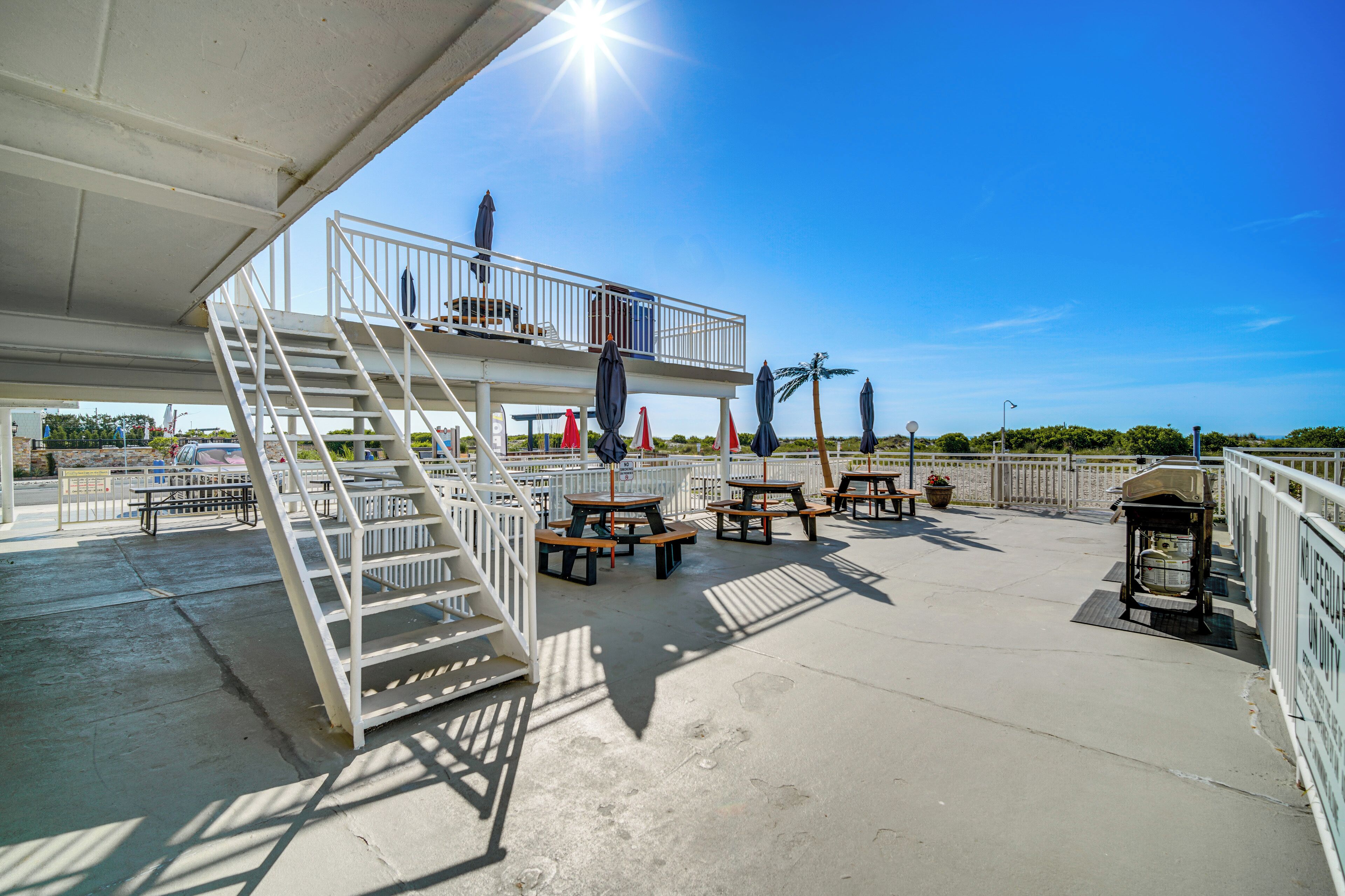 A rooftop deck with outdoor seating, a staircase, and a view of the beach.
