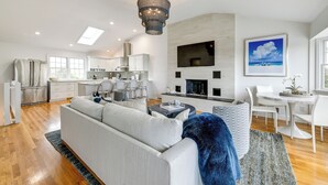A spacious living area with a sofa, a dining table, and a kitchen in the background. - Stunning Westhampton Beach Home w/ Private Pool (Westhampton Beach)