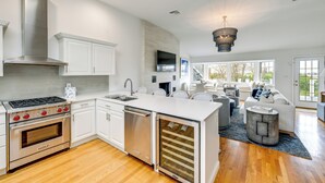 A modern kitchen with stainless steel appliances, white cabinetry, and a large island. - Stunning Westhampton Beach Home w/ Private Pool (Westhampton Beach)