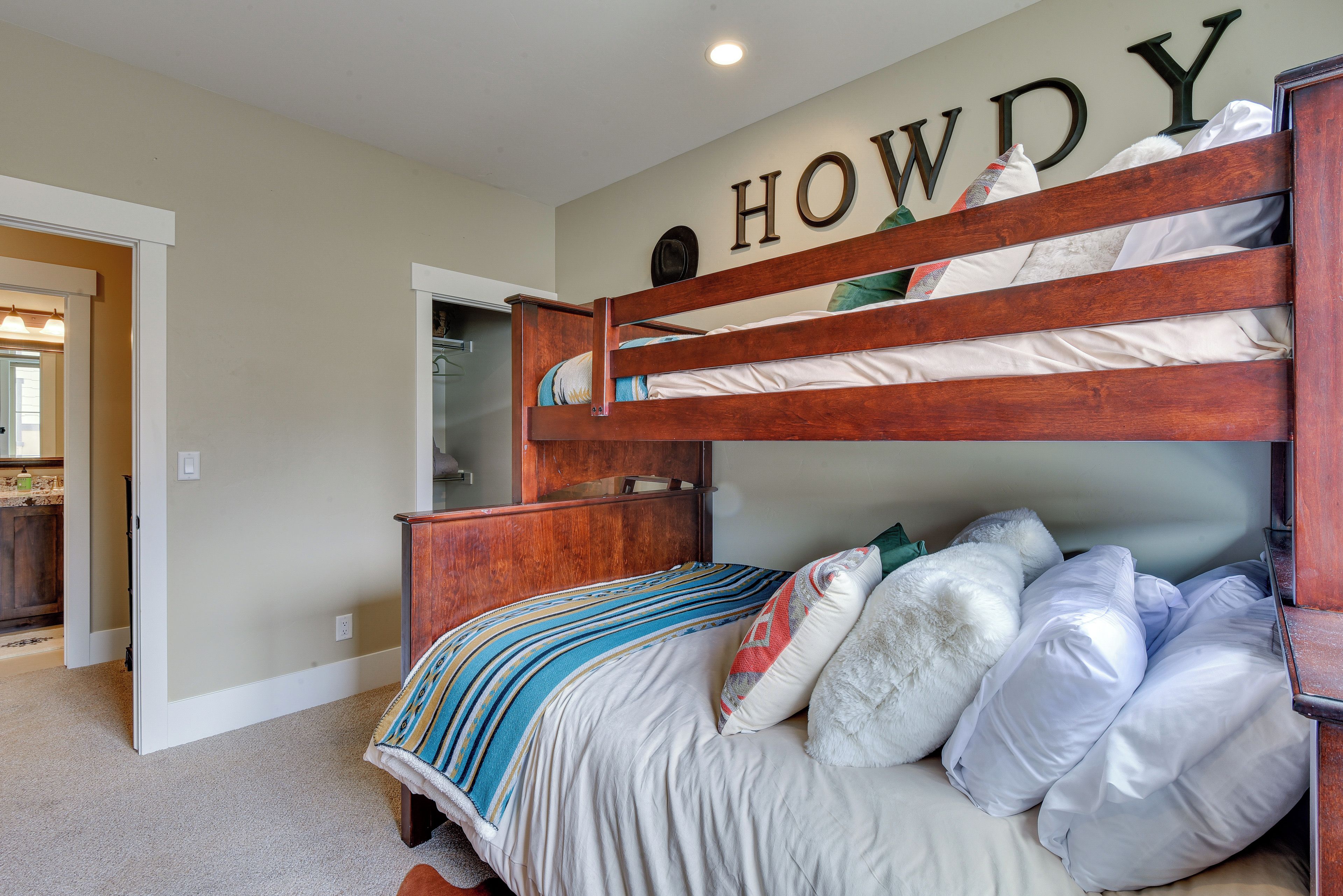 A bunk bed with a wooden headboard, multiple pillows, and a striped blanket.