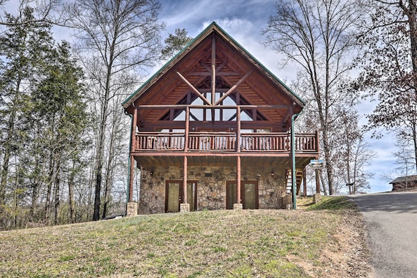 Eine zweistöckige Lodge mit Natursteinfassade, einem Balkon im Obergeschoss und einem Steingang.
