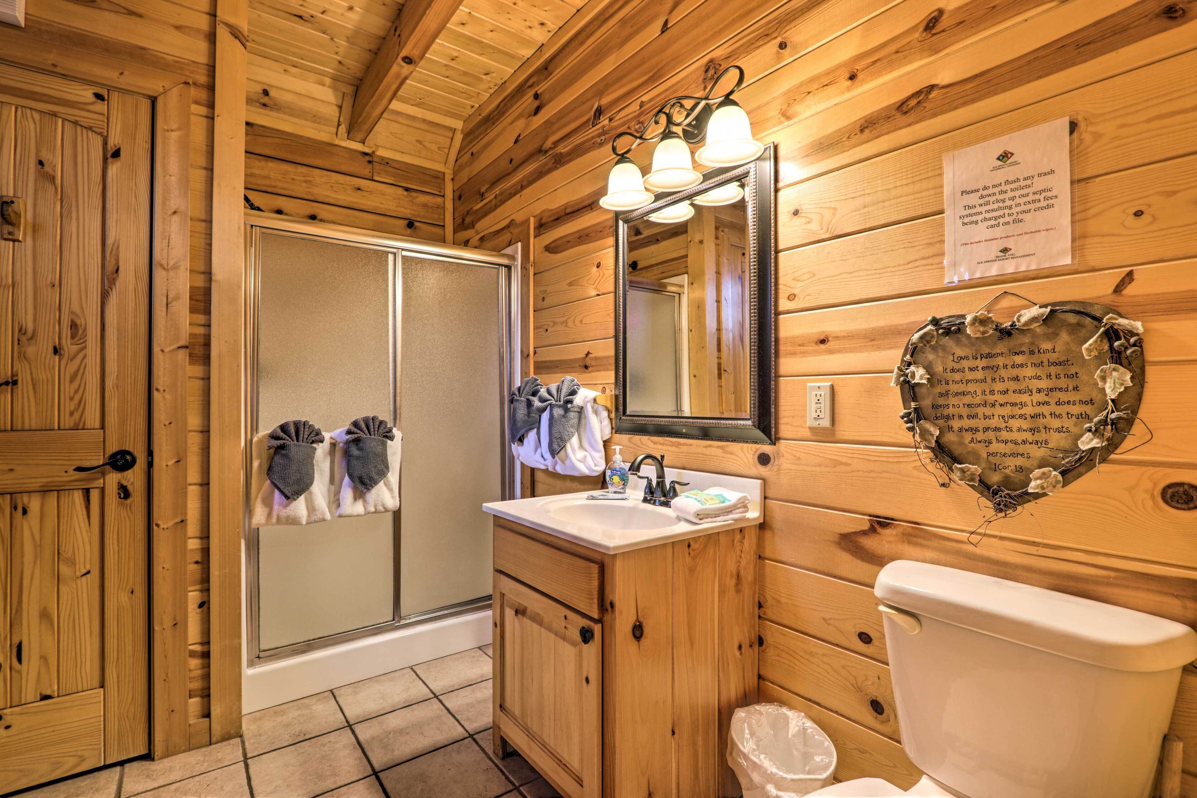Une salle de bain rustique, aménagée dans une cabane en bois, avec une douche, un lavabo et des toilettes.