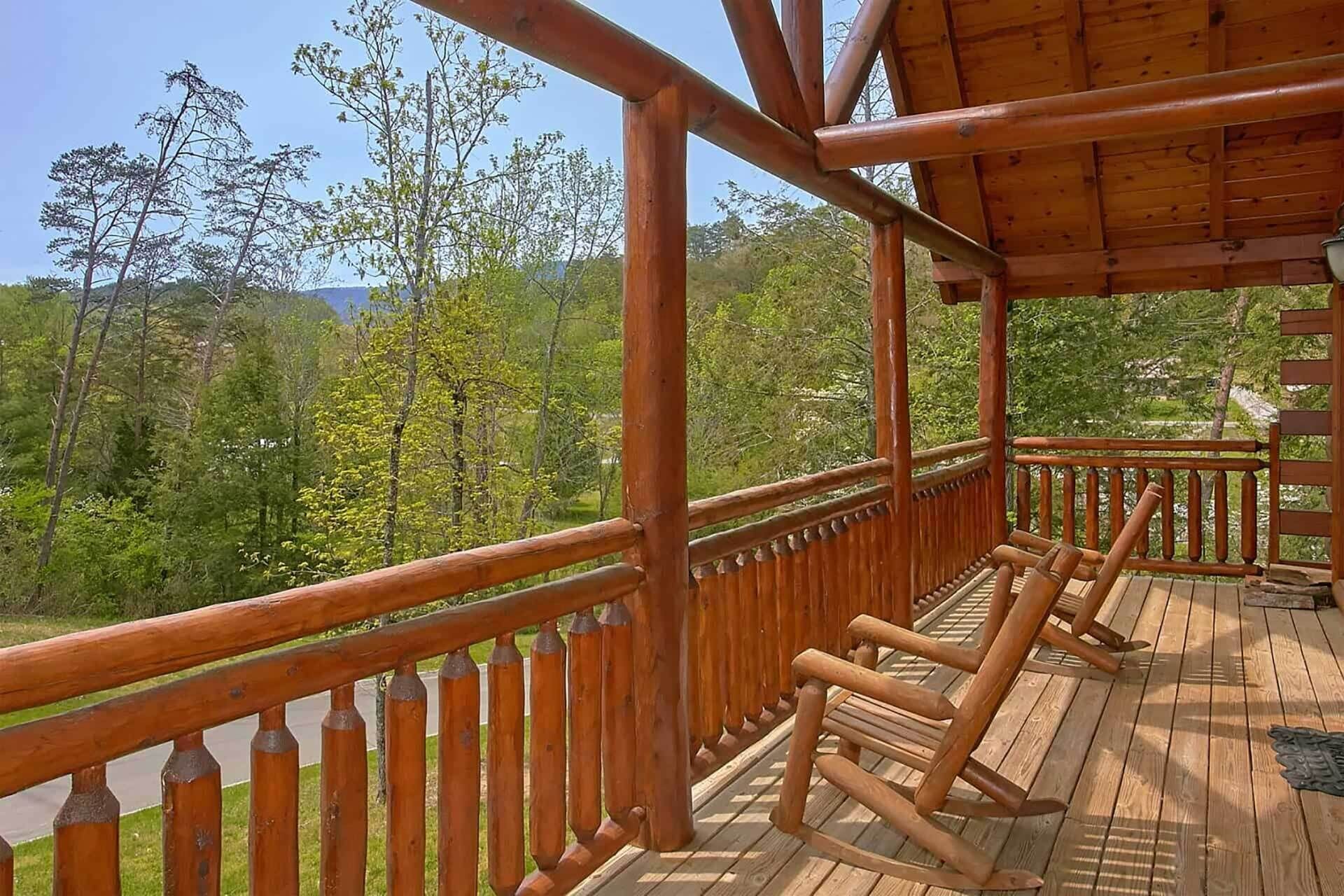 A wooden deck with a railing, overlooking a forested area.