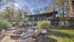 Un chalet rustique avec des fondations en pierre, une terrasse en bois et des drapeaux américains.
