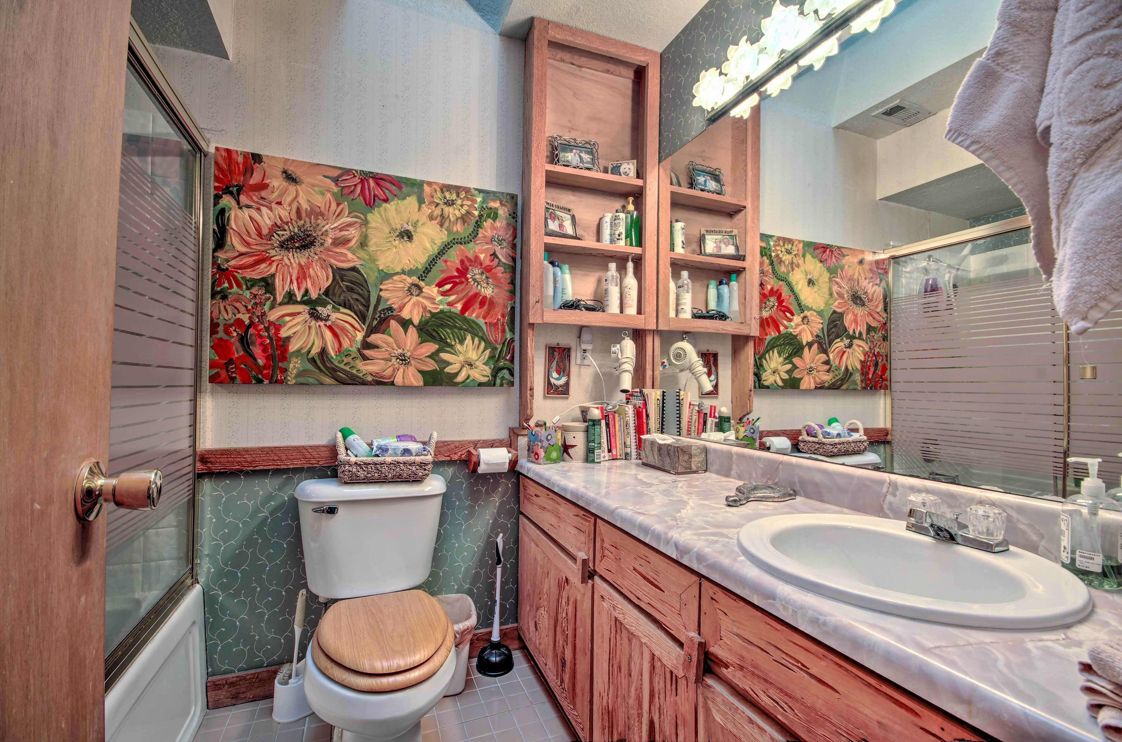 A bathroom with a toilet, sink, wooden cabinets, and a large mirror.