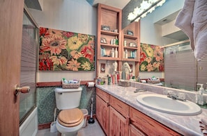 A bathroom with a toilet, sink, wooden cabinets, and a large mirror. - Riverfront Getaway w/ Treehouse, Fire Pit & Deck! (Mammoth Spring)