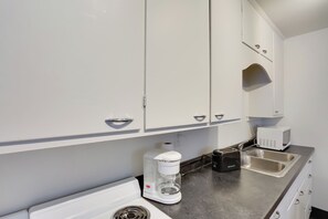 A kitchen with white cabinets, a coffee maker, a toaster, and a sink.