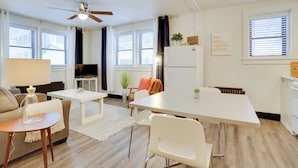 Una sala de estar moderna y bien iluminada, con sofá, mesa de centro, televisor y un comedor con mesa y sillas.