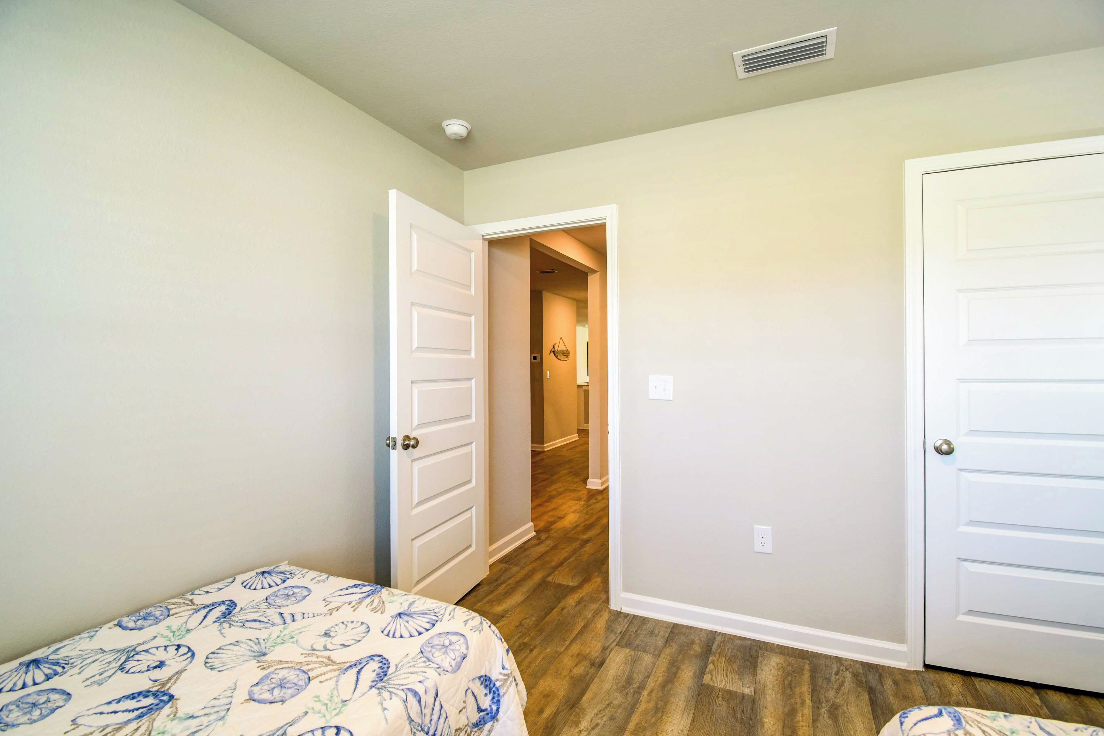 A bedroom with a bed, a door leading to a hallway, and a white door.