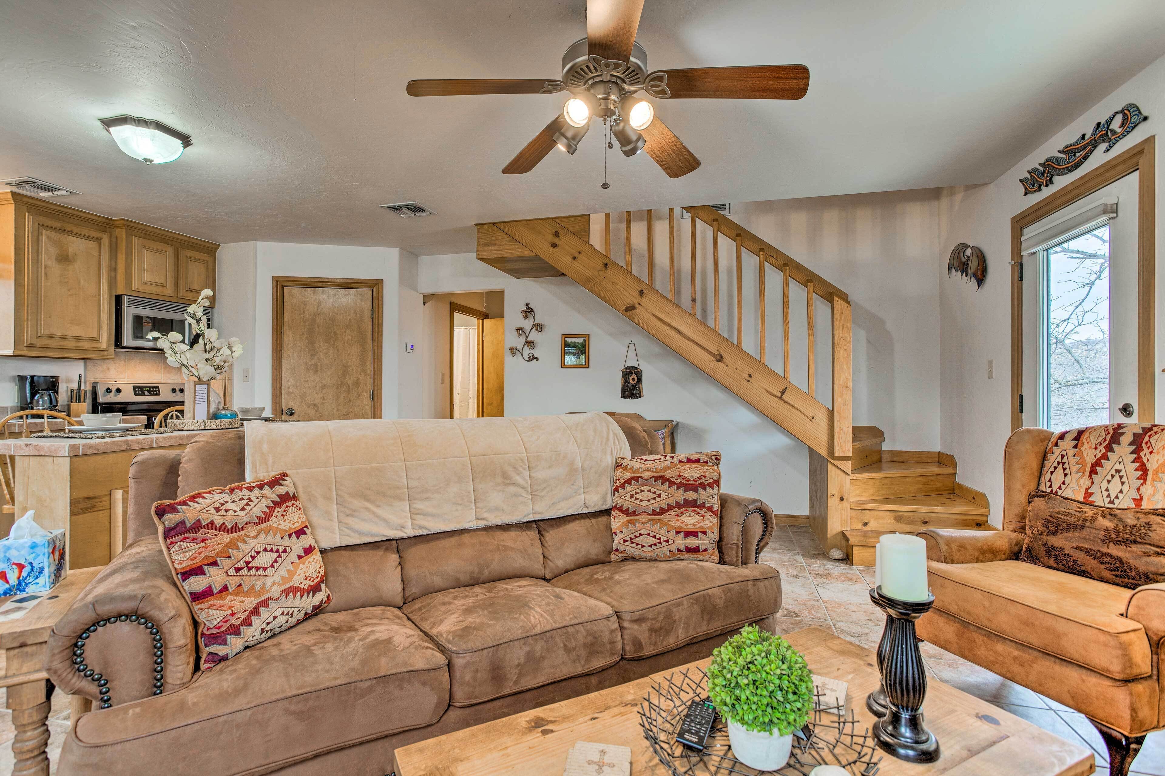 A spacious living room with a brown leather sofa, a wooden coffee table, and a staircase leading to an upper floor.