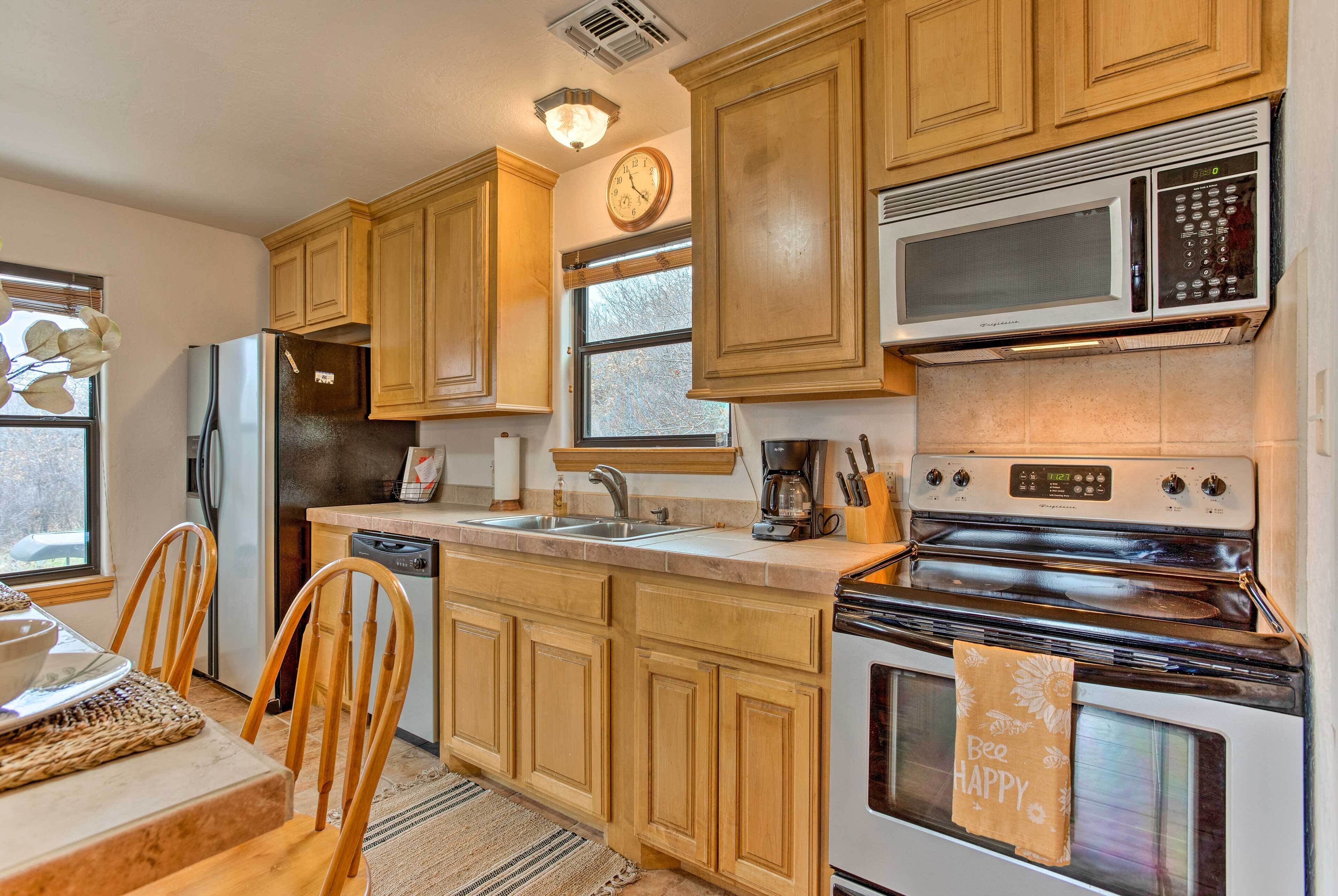 A kitchen with wooden cabinets, a stainless steel refrigerator, a microwave, an oven, and a sink.