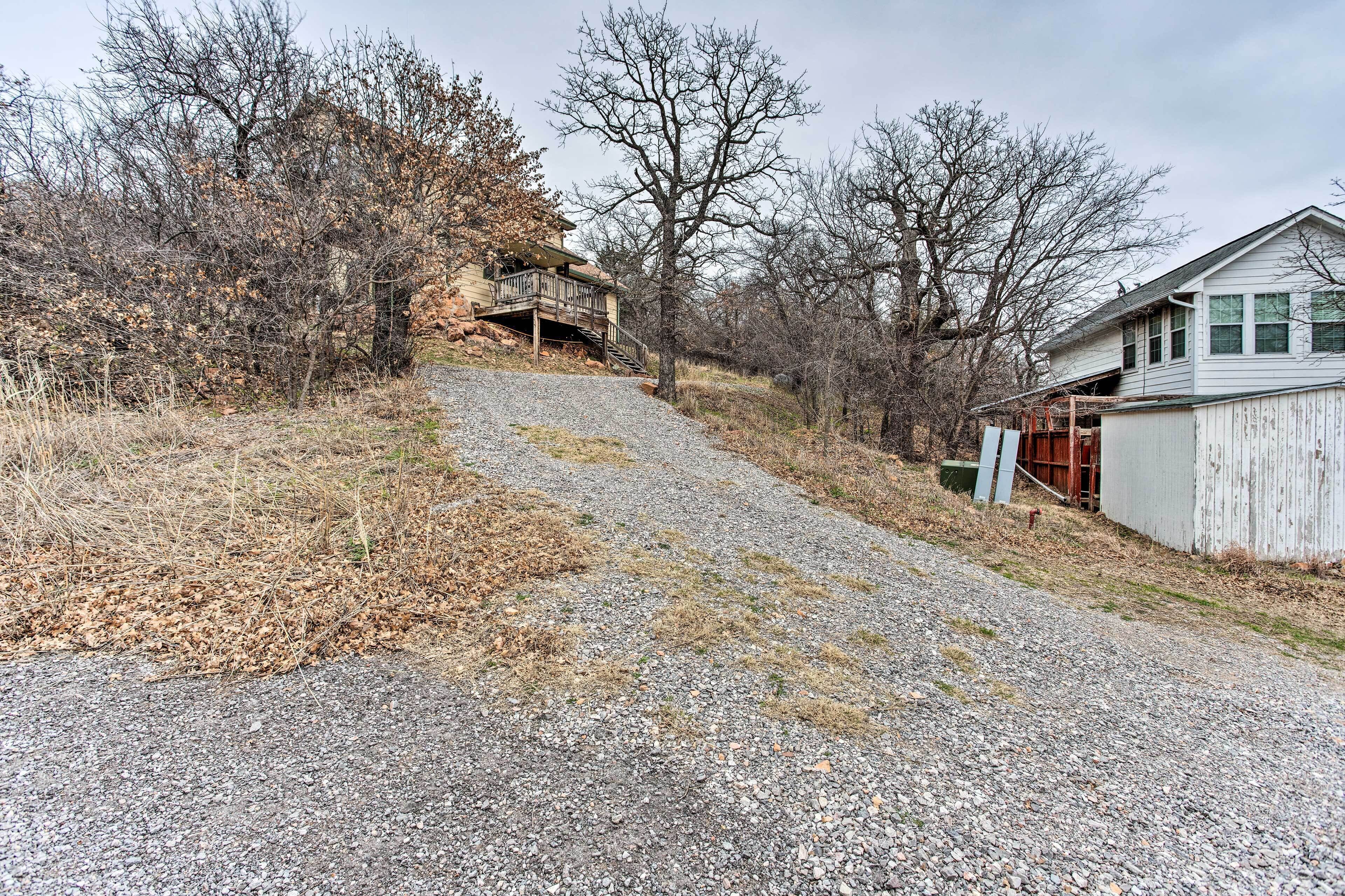 A gravel driveway leading to a house with a wooden deck and a garage.