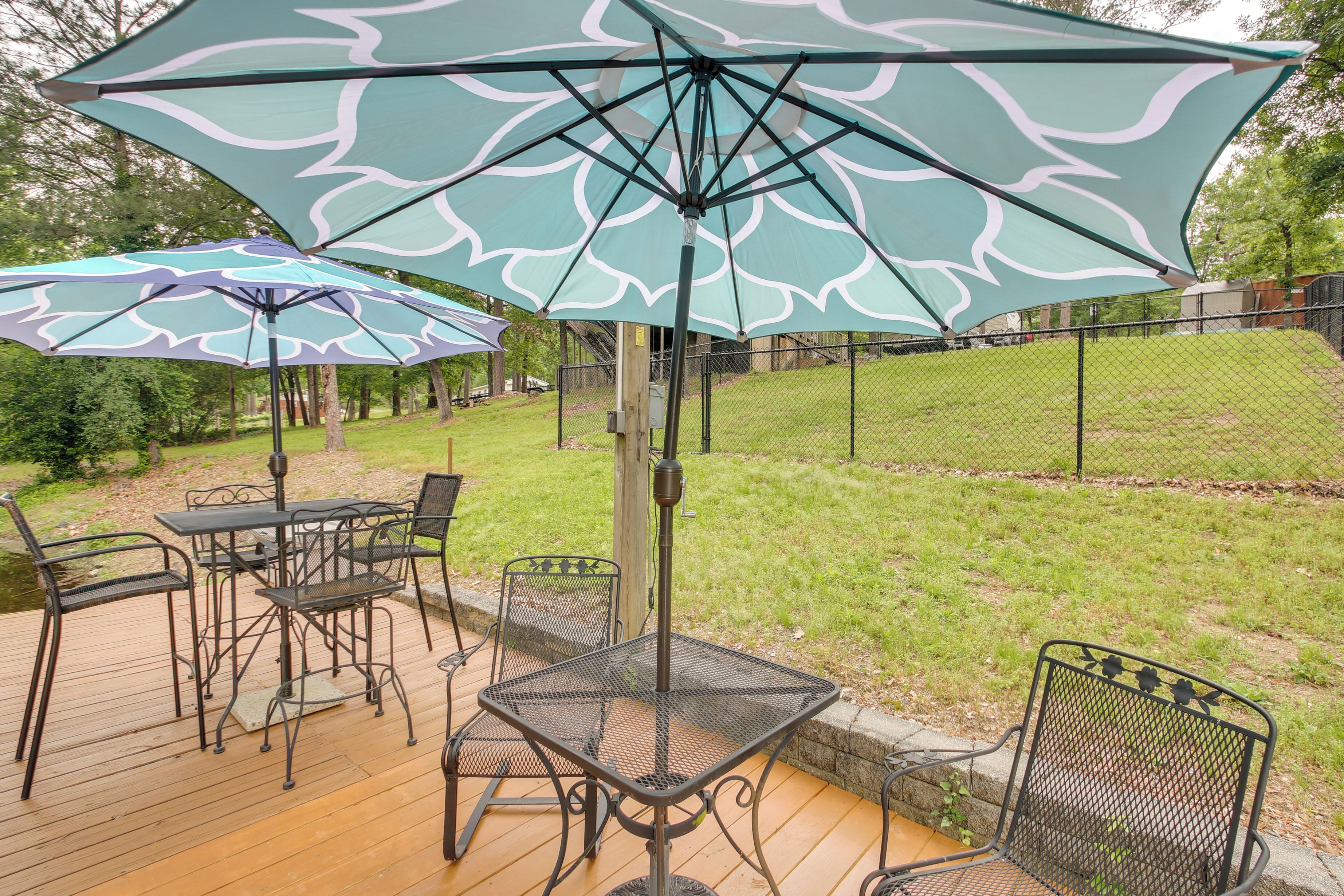 A patio area with a table and chairs, a large umbrella, and a grassy yard.