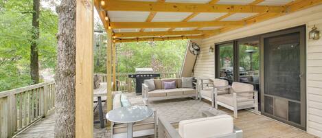 A covered outdoor deck with wooden beams, a grill, and seating.