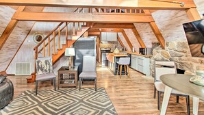 A spacious loft with a high ceiling, exposed wooden beams, a kitchen area, and a cozy seating area with a patterned rug. - Lake Hamilton Cabin: Boating Getaway! (Hot Springs)