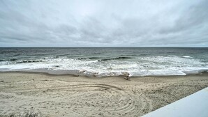 Una playa con olas rompiendo en la orilla y una zona arenosa con huellas.
