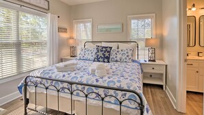 A bedroom with a bed, two bedside tables, a nightstand, a window with blinds, and a wall-mounted picture. - Steps to Sand: Hilton Head Retreat w/ Pool Access! (Hilton Head Island)