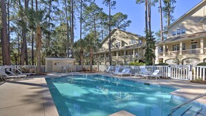 A swimming pool with a 3 FT depth marker, surrounded by lounge chairs and a white fence.