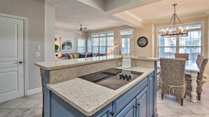 A kitchen with a granite countertop, built-in stove, and wicker chairs.