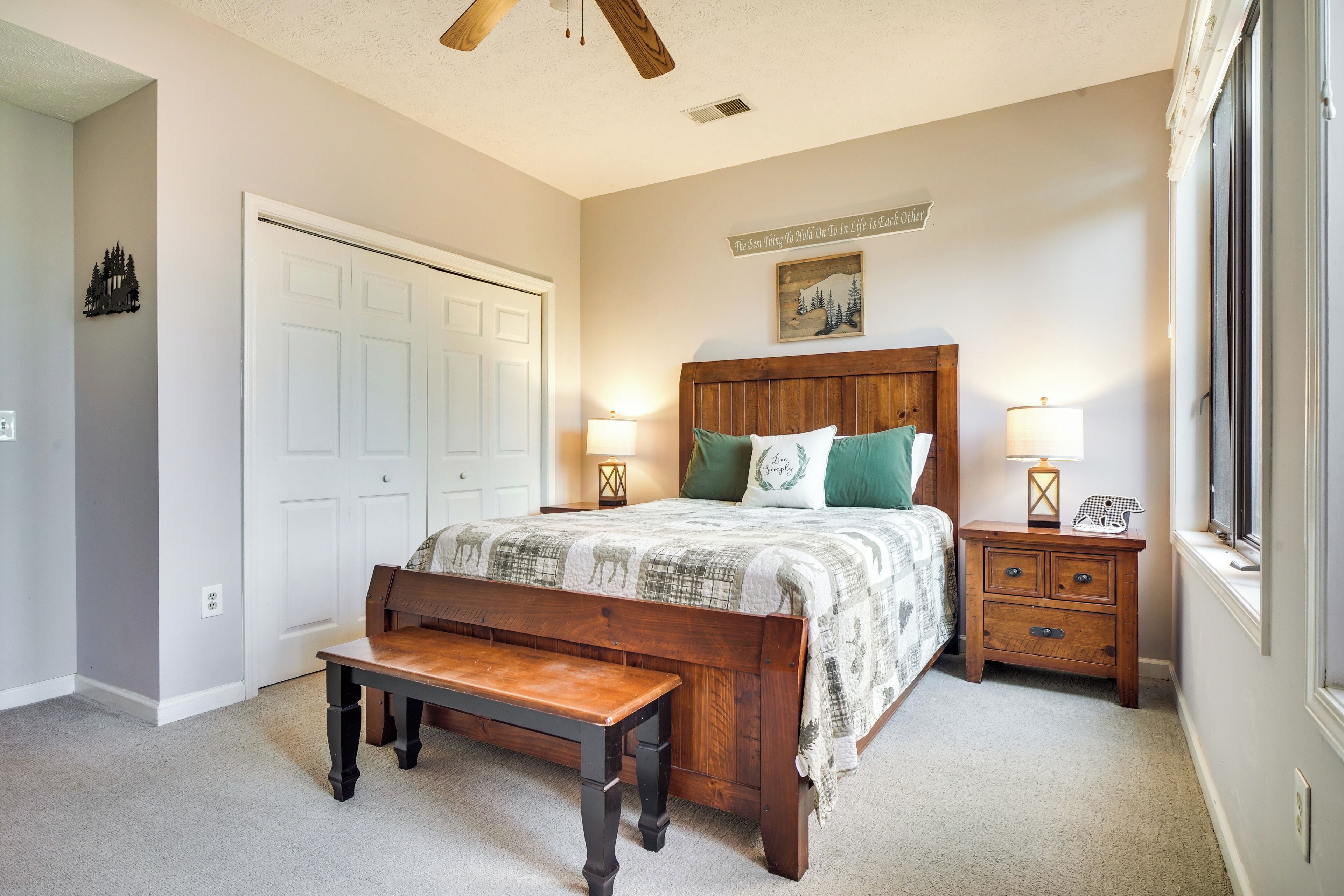 Une chambre à coucher avec un lit en bois, un banc, une table de chevet avec une lampe et une porte.