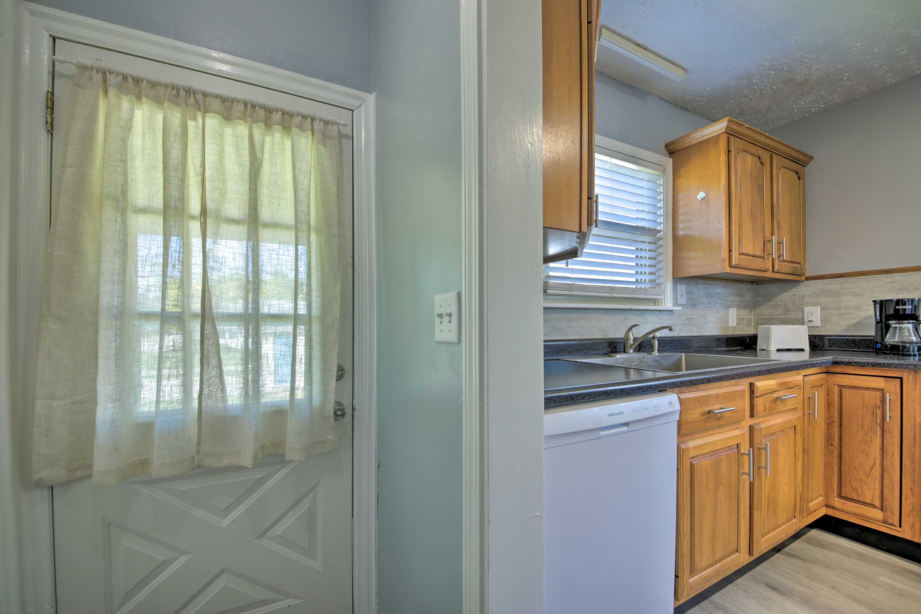 A kitchen with wooden cabinets, a dishwasher, a sink, and a window with blinds.