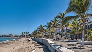 A coastal promenade with a concrete barrier, palm trees, and buildings in the background. - Sweet & Chic Puerto Vallarta Condo: Walk to Beach! (Puerto Vallarta)