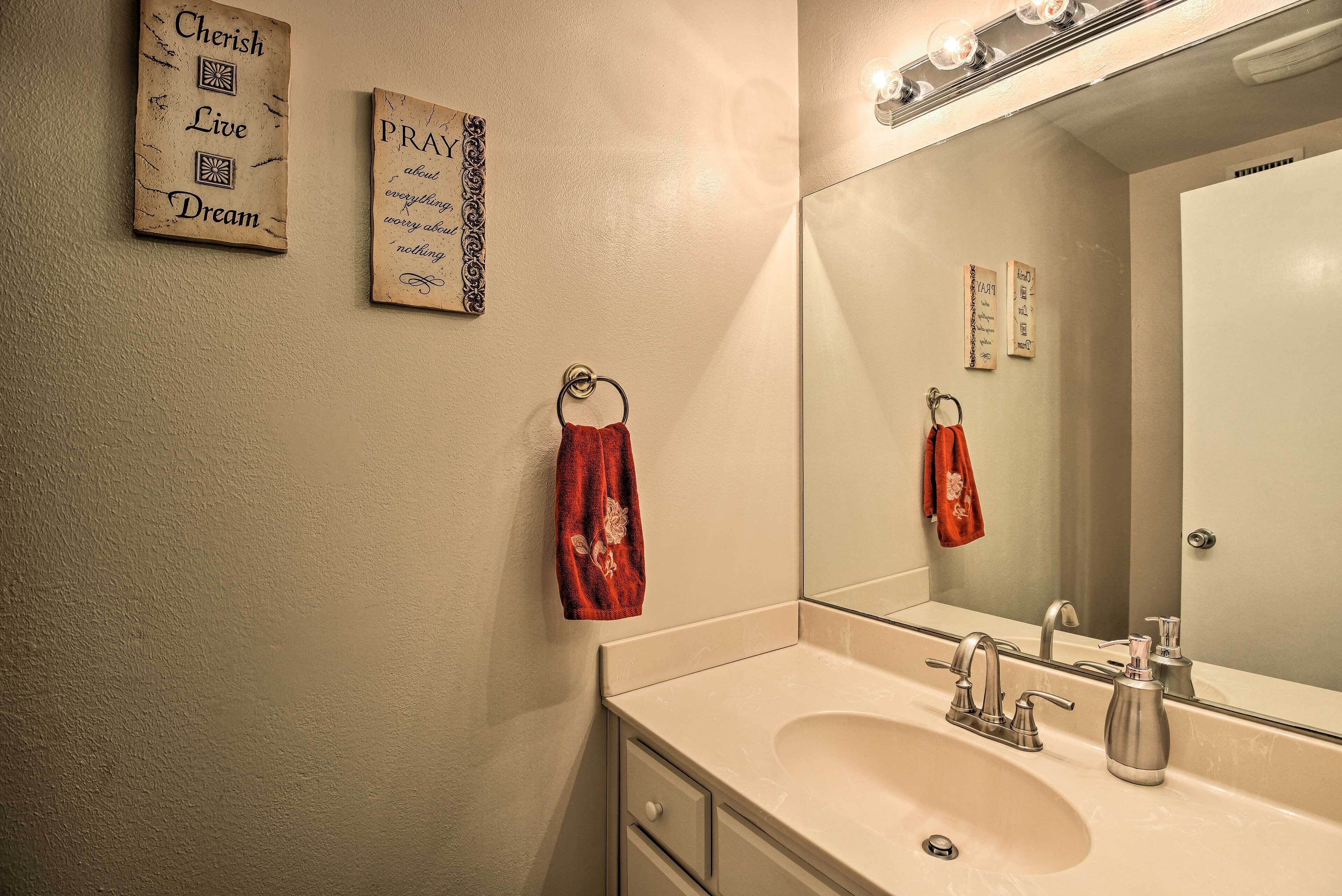 Une salle de bain équipée d’un lavabo, d’un miroir, d’un porte-serviettes et de quelques éléments de décoration murale.