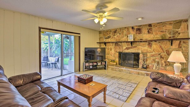 A living room with a stone fireplace, leather sofas, a coffee table, and a television.