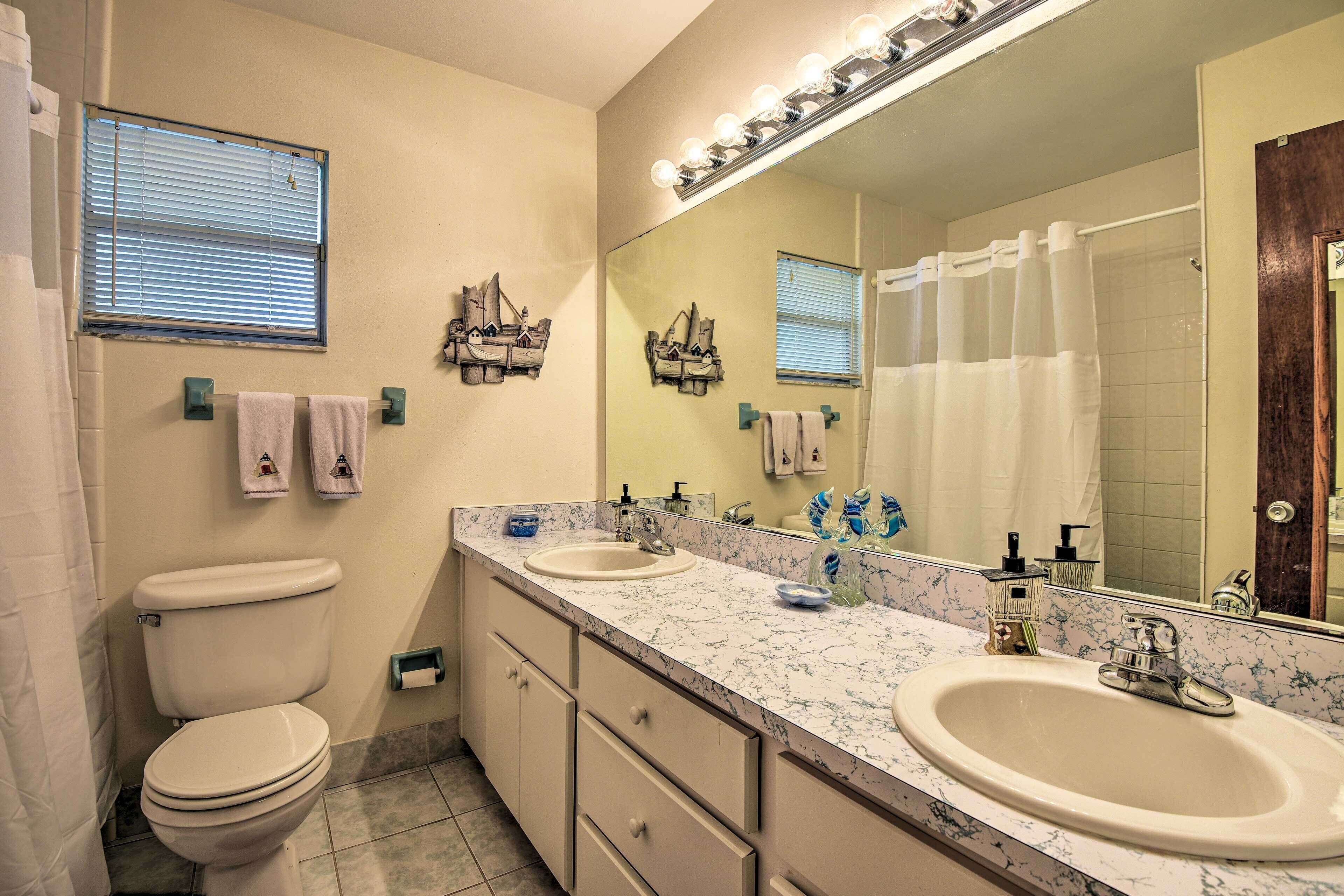 A bathroom with a toilet, sink, and mirror.