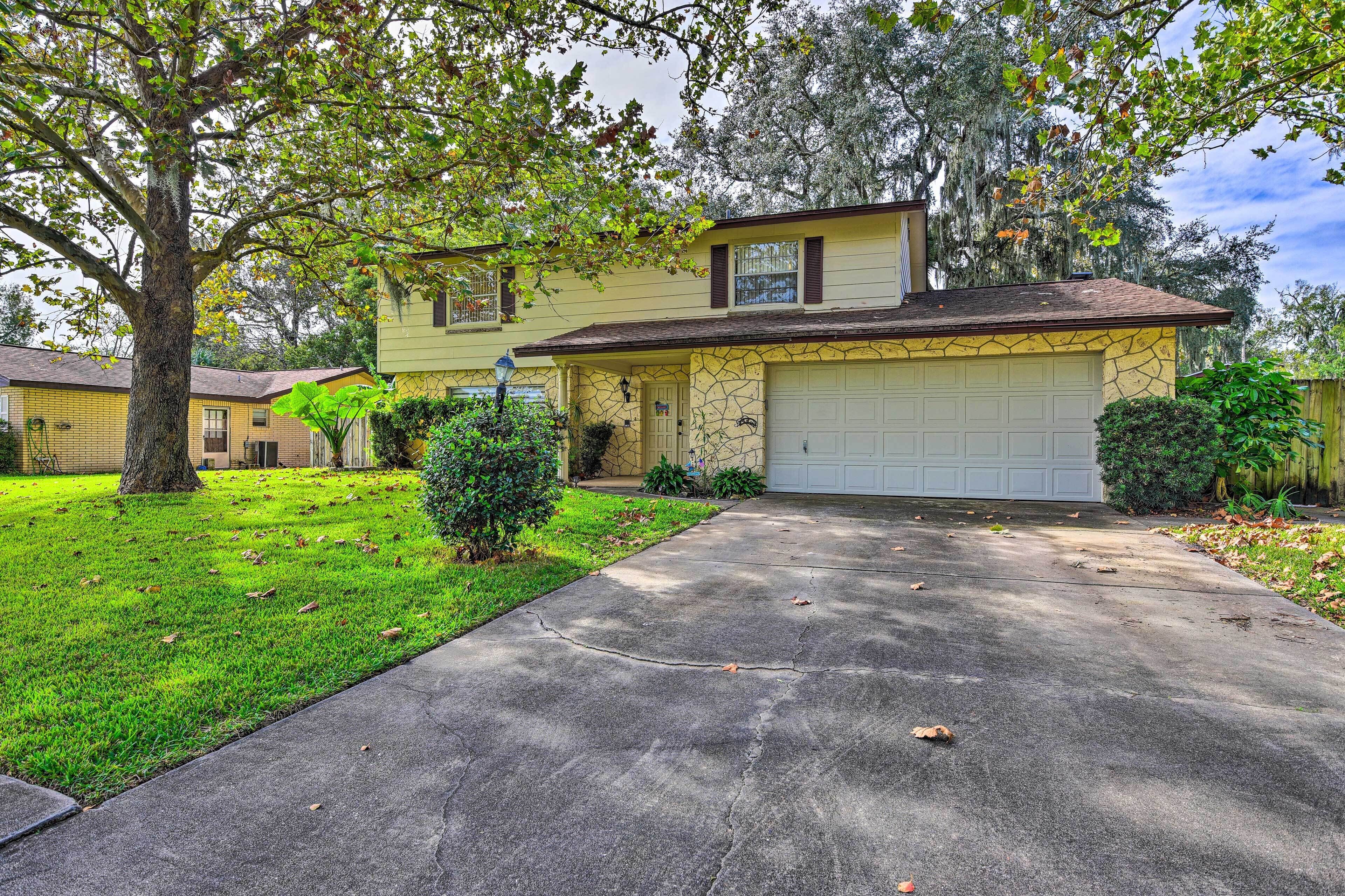 A two-story house with a garage, surrounded by a well-maintained lawn and mature trees.