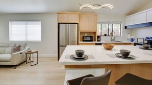 Une cuisine moderne dotée d’un îlot central, d’appareils électroménagers intégrés et d’un coin repas avec des chaises.