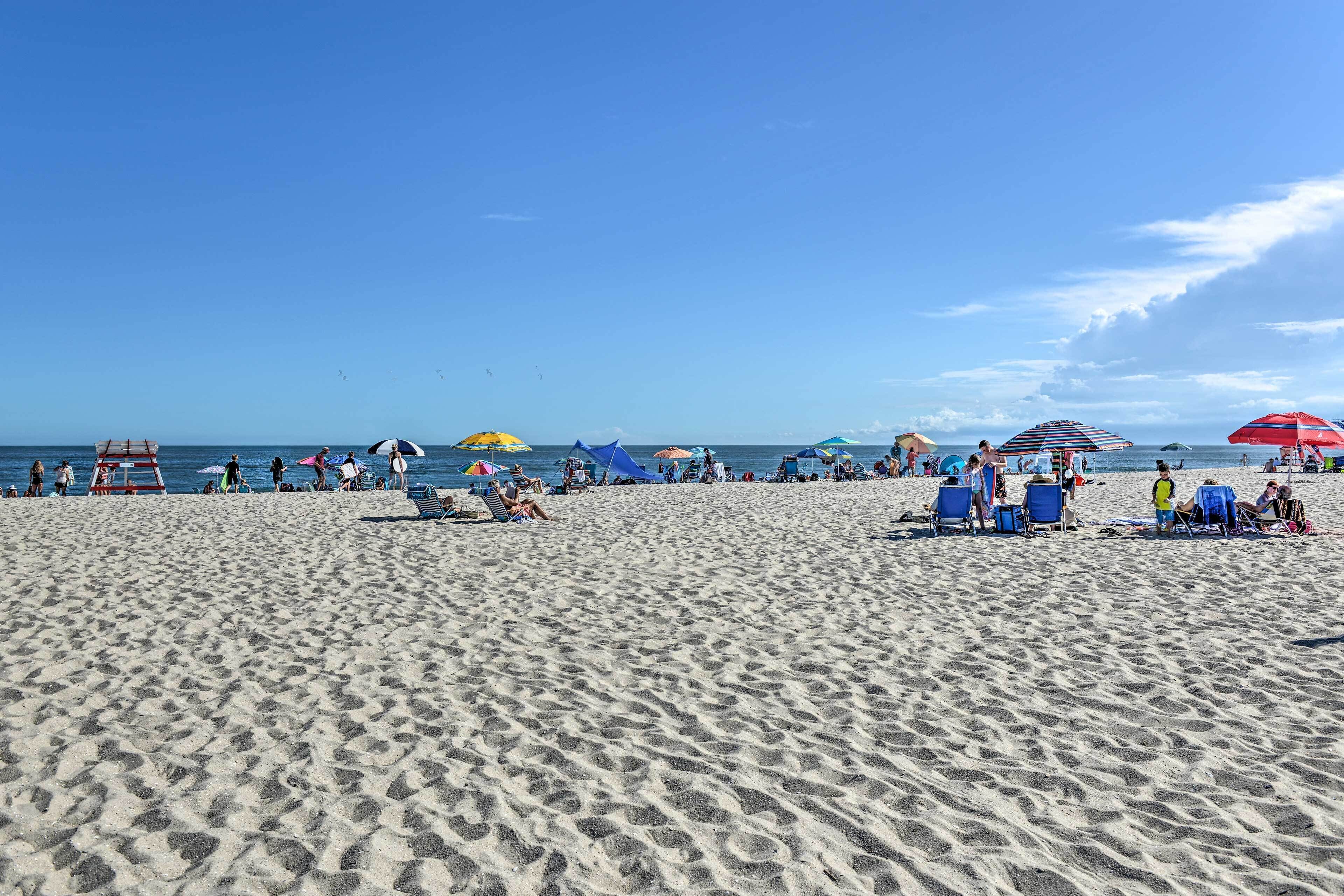 A sandy beach with people and umbrellas.