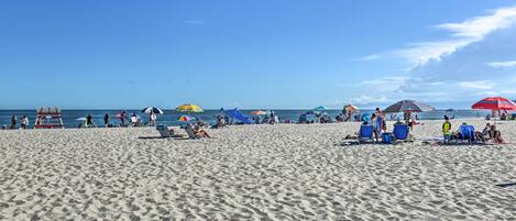 A sandy beach with people and umbrellas.