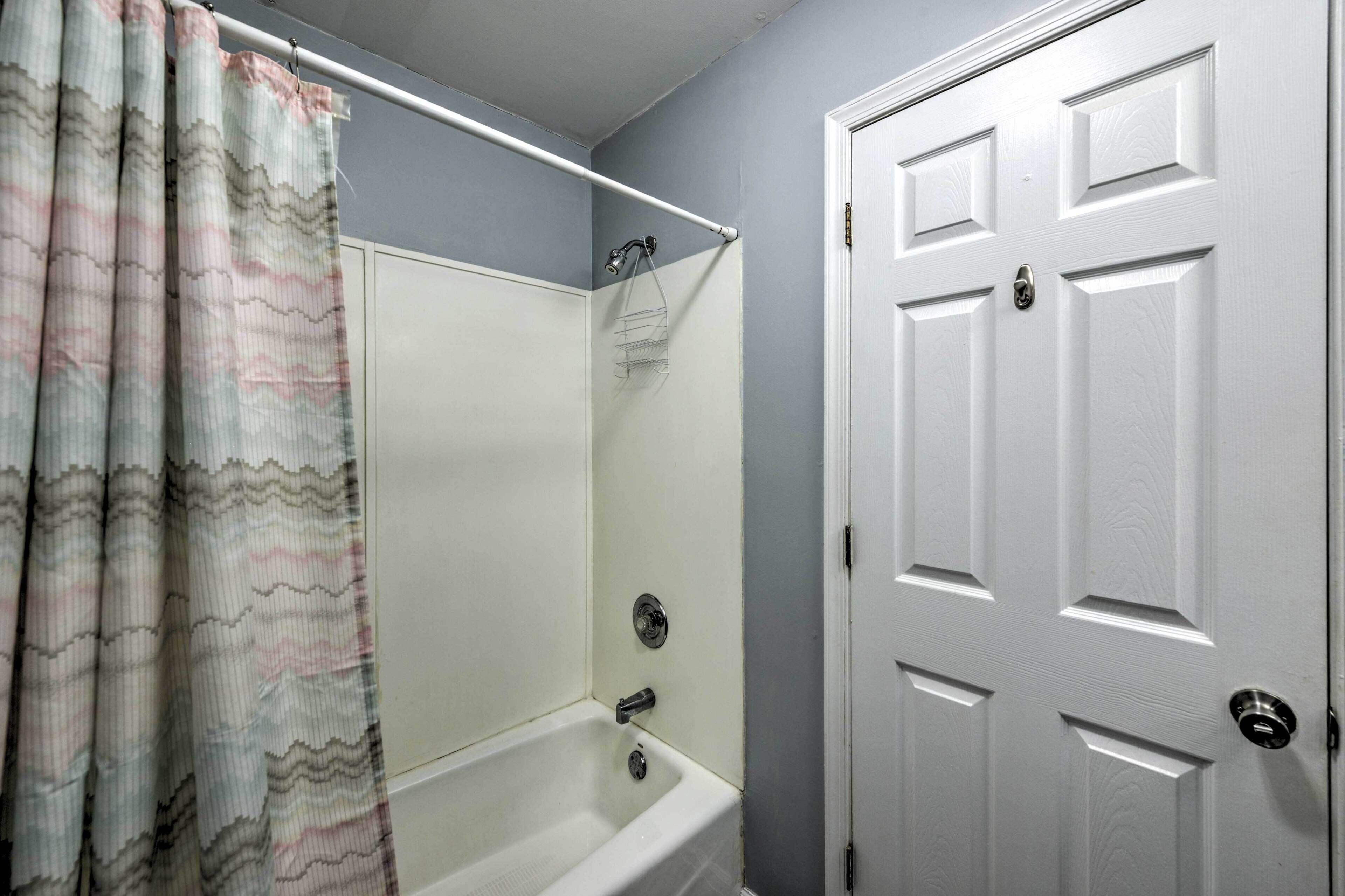 A bathroom with a bathtub, shower curtain, and a white door.